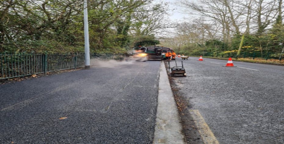 Newly reinstated footway beside a lighting column, with works continuing under traffic management